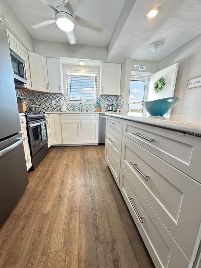 2860 Ocean Shore Blvd Unit 5020, Ormond Beach, FL 32176 - kitchen featuring stainless steel appliances, white cabinets, dark wood finished floors, tasteful backsplash, and light countertops