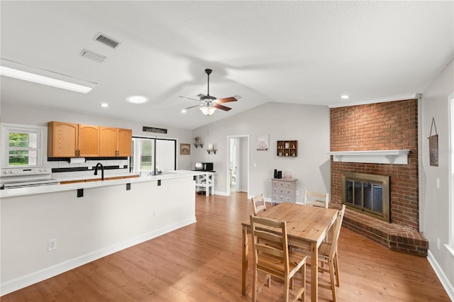 2455 Whooping Crane Dr, De Leon Springs, FL 32130 - dining room featuring light wood-type flooring, a brick fireplace, vaulted ceiling, ceiling fan, and recessed lighting