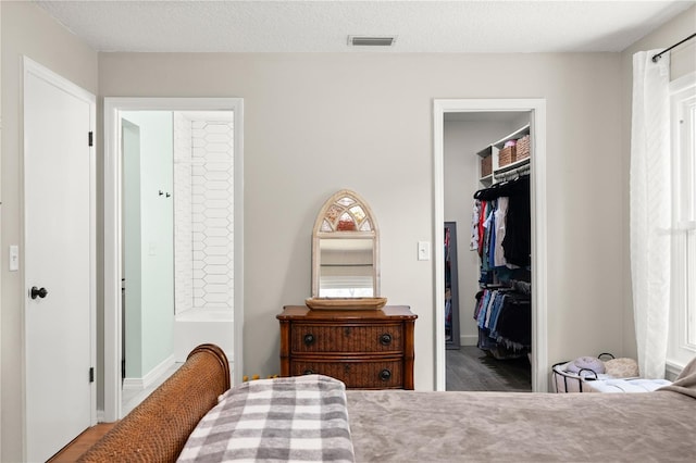 2455 Whooping Crane Dr, De Leon Springs, FL 32130 - bedroom featuring a walk in closet, a closet, wood finished floors, and ensuite bath