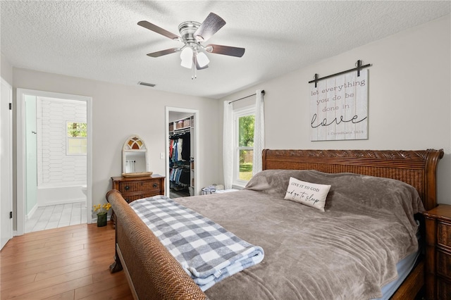 2455 Whooping Crane Dr, De Leon Springs, FL 32130 - bedroom with wood finished floors, a walk in closet, a textured ceiling, a closet, and ensuite bath