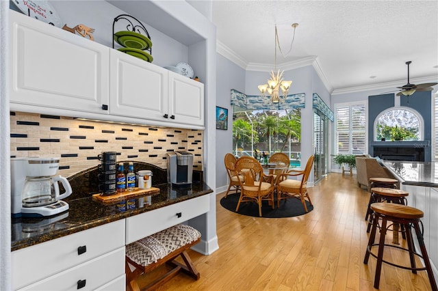 801 Arbor Glen Ct, Ormond Beach, FL 32174 - kitchen with light wood finished floors, a chandelier, backsplash, white cabinetry, and ornamental molding