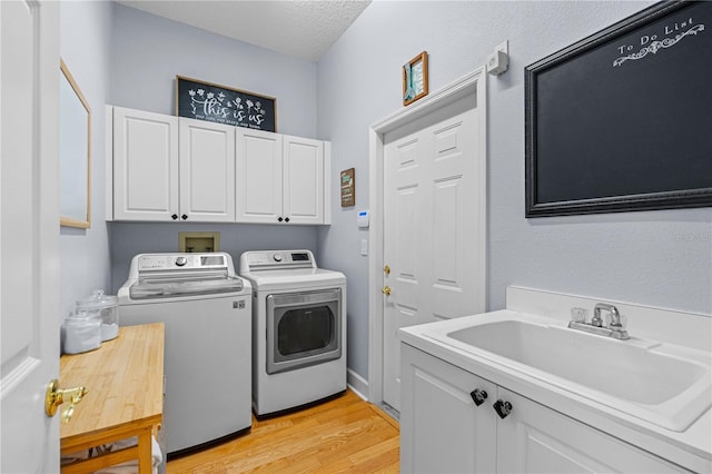 801 Arbor Glen Ct, Ormond Beach, FL 32174 - washroom featuring washing machine and clothes dryer, light wood-style flooring, cabinet space, and a textured ceiling