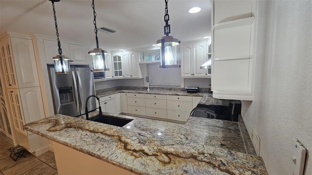 3510 Magnolia Way, Punta Gorda, FL 33950 - kitchen with stainless steel refrigerator with ice dispenser, a peninsula, white cabinets, under cabinet range hood, and hanging light fixtures