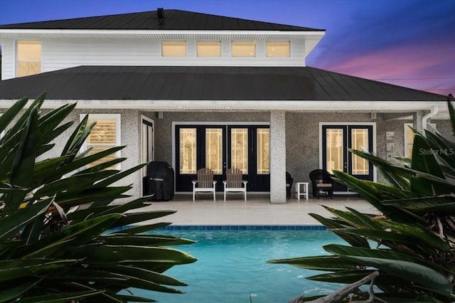 113 Neptune Ave, Ormond Beach, FL 32176 - back of property with a patio, an outdoor pool, a metal roof, stucco siding, and french doors