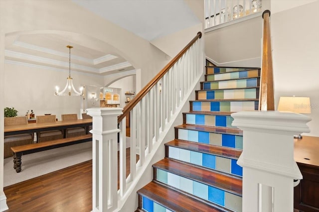 113 Neptune Ave, Ormond Beach, FL 32176 - stairs with wood finished floors, a raised ceiling, arched walkways, a chandelier, and crown molding