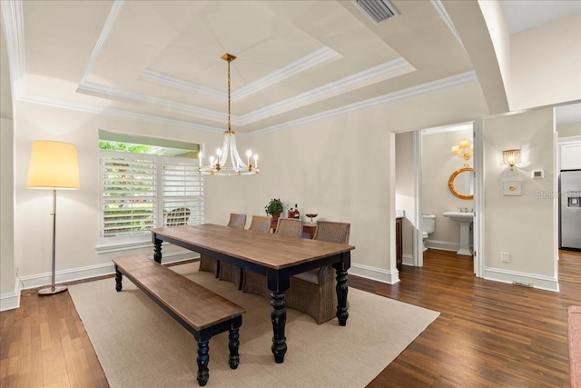113 Neptune Ave, Ormond Beach, FL 32176 - dining room with a chandelier, a raised ceiling, dark wood-type flooring, ornamental molding, and arched walkways