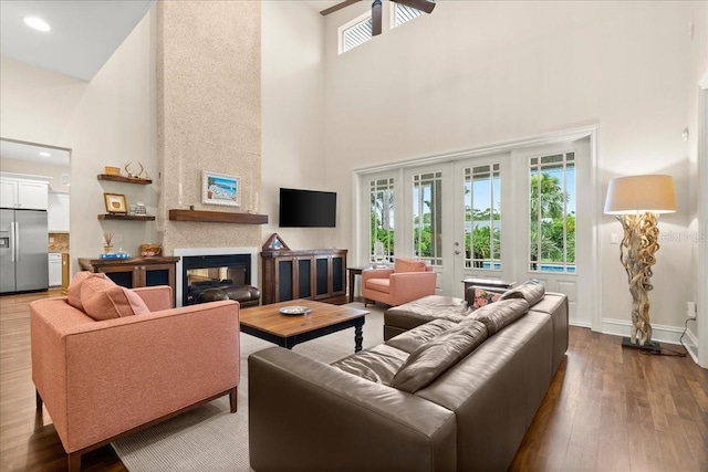 113 Neptune Ave, Ormond Beach, FL 32176 - living room featuring a towering ceiling, ceiling fan, dark wood-style floors, french doors, and a multi sided fireplace