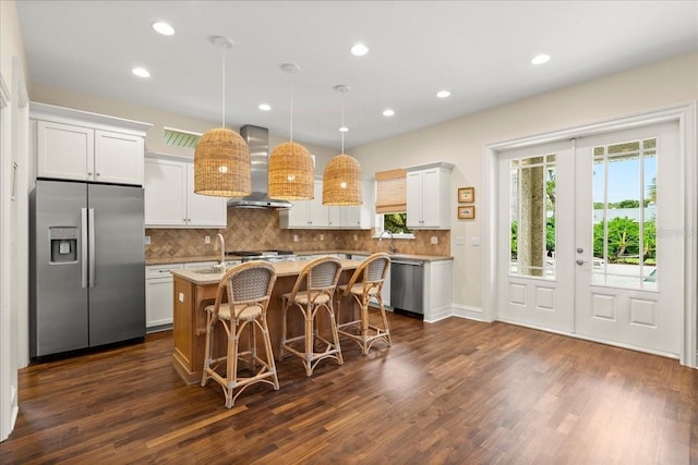 113 Neptune Ave, Ormond Beach, FL 32176 - kitchen featuring appliances with stainless steel finishes, wall chimney exhaust hood, dark wood finished floors, a center island with sink, and decorative backsplash