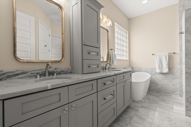 113 Neptune Ave, Ormond Beach, FL 32176 - bathroom with double vanity, a freestanding tub, tile walls, marble look tile flooring, and wainscoting
