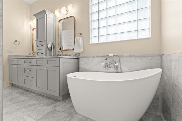 113 Neptune Ave, Ormond Beach, FL 32176 - bathroom featuring marble finish floors, tile walls, plenty of natural light, double vanity, and a freestanding tub