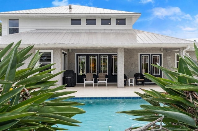 113 Neptune Ave, Ormond Beach, FL 32176 - rear view of house with a patio area, stucco siding, an outdoor pool, a metal roof, and french doors