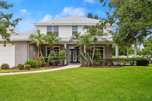 113 Neptune Ave, Ormond Beach, FL 32176 - view of front of home with a front yard, an attached garage, stucco siding, and a metal roof
