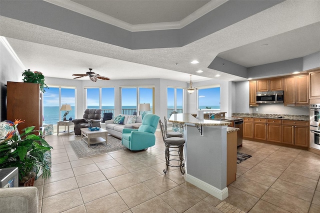 2901 S Atlantic Ave Unit 603, Daytona Beach Shores, FL 32118 - kitchen featuring stainless steel appliances, open floor plan, ornamental molding, a kitchen bar, and light tile patterned floors