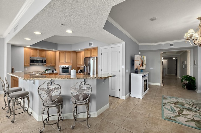 2901 S Atlantic Ave Unit 603, Daytona Beach Shores, FL 32118 - kitchen featuring appliances with stainless steel finishes, light tile patterned flooring, light stone counters, a breakfast bar area, and a textured ceiling