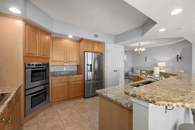 2901 S Atlantic Ave Unit 603, Daytona Beach Shores, FL 32118 - kitchen featuring appliances with stainless steel finishes, a kitchen breakfast bar, a chandelier, light tile patterned floors, and light stone counters