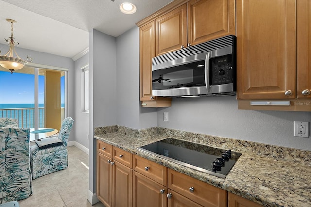 2901 S Atlantic Ave Unit 603, Daytona Beach Shores, FL 32118 - kitchen with stainless steel microwave, black electric cooktop, light tile patterned flooring, light stone counters, and decorative light fixtures