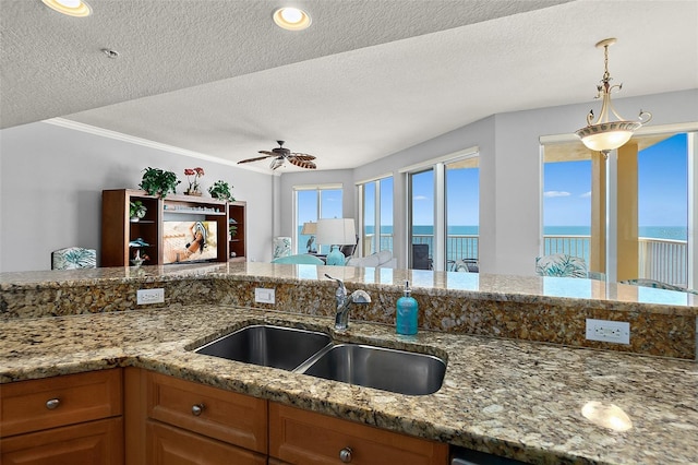 2901 S Atlantic Ave Unit 603, Daytona Beach Shores, FL 32118 - kitchen with a ceiling fan, a textured ceiling, brown cabinets, light stone countertops, and decorative light fixtures
