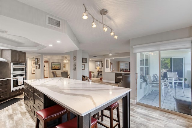 1 John Anderson Dr Unit 1030, Ormond Beach, FL 32176 - kitchen with double oven, a kitchen bar, light wood-style floors, and light stone countertops