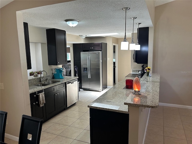 879 S Hancock Dr, Deltona, FL 32725 - kitchen with appliances with stainless steel finishes, a peninsula, light tile patterned floors, dark cabinetry, and light stone counters