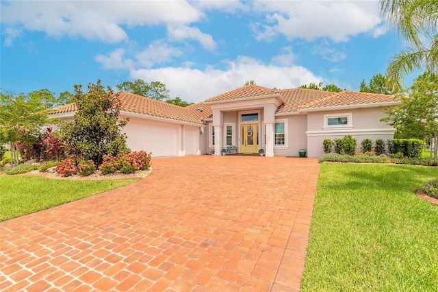 2816 E Venetian Lake Cir, New Smyrna Beach, FL 32168 - mediterranean / spanish-style house with stucco siding, decorative driveway, a tile roof, a garage, and a front yard