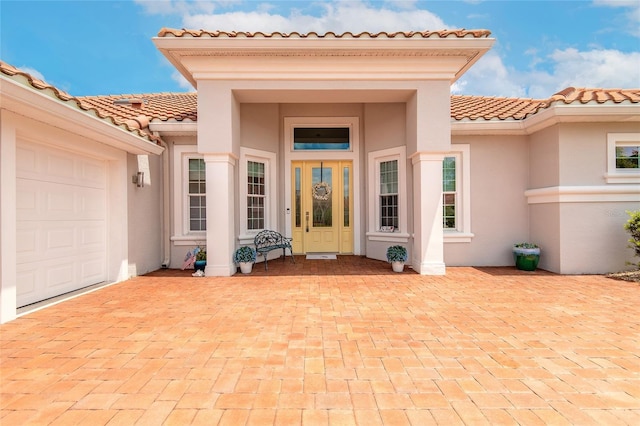 2816 E Venetian Lake Cir, New Smyrna Beach, FL 32168 - property entrance with stucco siding, a tile roof, an attached garage, and decorative driveway