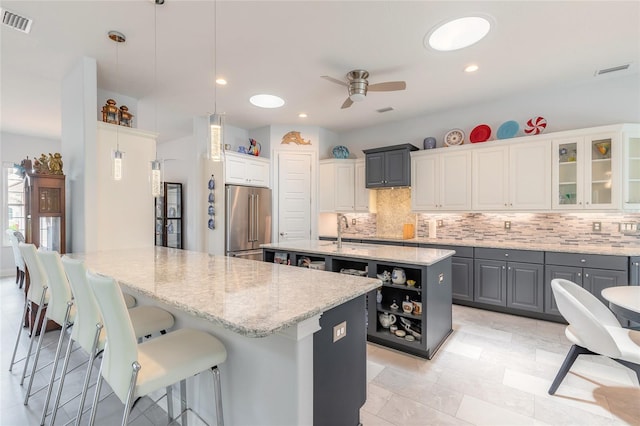 2816 E Venetian Lake Cir, New Smyrna Beach, FL 32168 - kitchen with high quality fridge, a ceiling fan, decorative backsplash, a center island with sink, and a breakfast bar area