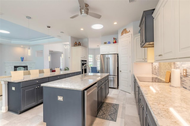 2816 E Venetian Lake Cir, New Smyrna Beach, FL 32168 - kitchen with appliances with stainless steel finishes, a center island with sink, ceiling fan, tasteful backsplash, and light stone countertops