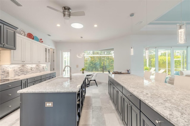 2816 E Venetian Lake Cir, New Smyrna Beach, FL 32168 - kitchen with ceiling fan, recessed lighting, tasteful backsplash, light stone counters, and hanging light fixtures