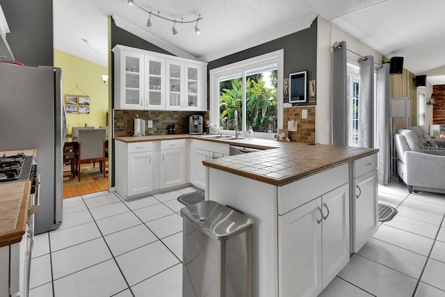 1366 Valhalla St, Deltona, FL 32725 - kitchen featuring light tile patterned floors, decorative backsplash, vaulted ceiling, glass insert cabinets, and a textured ceiling