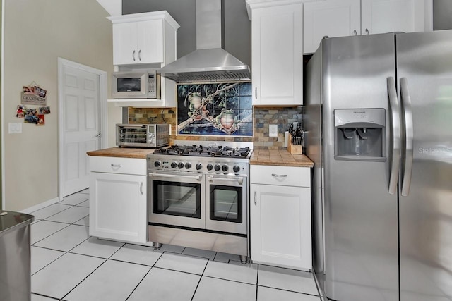 1366 Valhalla St, Deltona, FL 32725 - kitchen featuring stainless steel appliances, wall chimney exhaust hood, tasteful backsplash, white cabinetry, and light tile patterned flooring