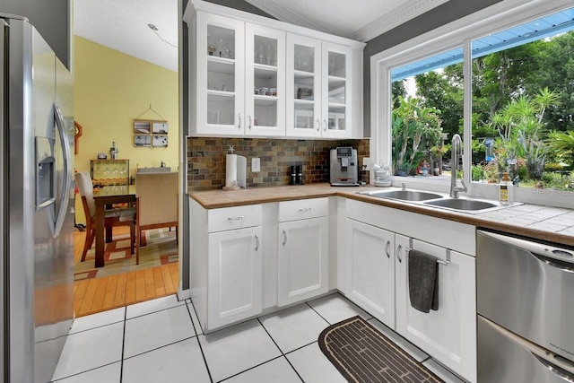 1366 Valhalla St, Deltona, FL 32725 - kitchen with stainless steel appliances, backsplash, light tile patterned flooring, white cabinetry, and vaulted ceiling