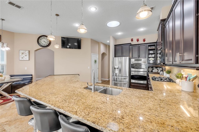 710 Grape Ivy Ln, New Smyrna Beach, FL 32168 - kitchen with arched walkways, appliances with stainless steel finishes, light stone countertops, pendant lighting, and a kitchen bar