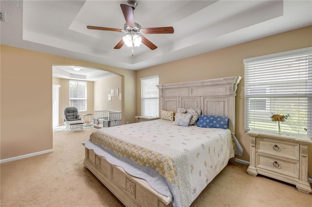710 Grape Ivy Ln, New Smyrna Beach, FL 32168 - bedroom with a raised ceiling, light carpet, arched walkways, and a ceiling fan