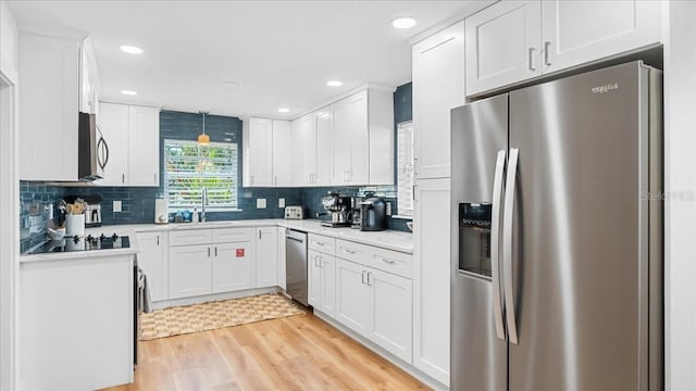 943 S Atlantic Ave, Cocoa Beach, FL 32931 - kitchen with appliances with stainless steel finishes, light wood finished floors, white cabinets, light countertops, and tasteful backsplash