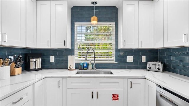 943 S Atlantic Ave, Cocoa Beach, FL 32931 - kitchen featuring stainless steel dishwasher, white cabinetry, backsplash, and light stone counters