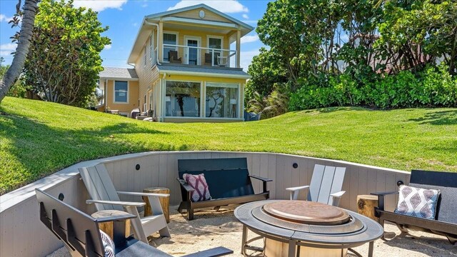 943 S Atlantic Ave, Cocoa Beach, FL 32931 - back of property with a fire pit, a lawn, and a balcony