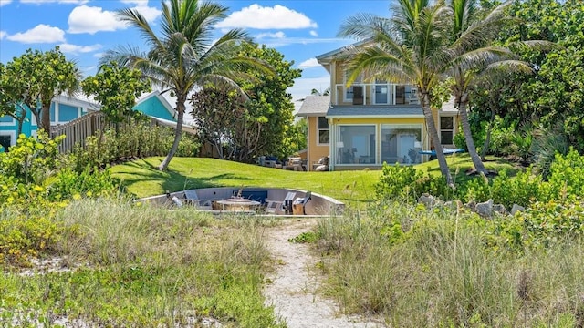 943 S Atlantic Ave, Cocoa Beach, FL 32931 - view of grassy yard with a fire pit and a sunroom