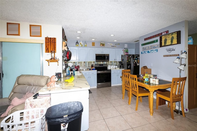 4831 Cypress Tree Dr, Tampa, FL 33624 - kitchen with stainless steel appliances, light countertops, light tile patterned flooring, a textured ceiling, and white cabinets