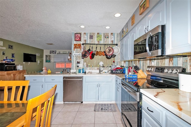 4831 Cypress Tree Dr, Tampa, FL 33624 - kitchen featuring appliances with stainless steel finishes, a textured ceiling, white cabinetry, light countertops, and light tile patterned floors