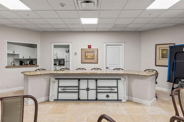 4 Oceans W Blvd Unit 308C, Daytona Beach, FL 32118 - kitchen featuring white cabinetry, freestanding refrigerator, light stone counters, light tile patterned flooring, and a paneled ceiling