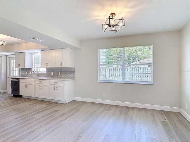 1019 Chippewa Trl, Daytona Beach, FL 32117 - kitchen with dishwasher, light countertops, light wood-style floors, white cabinets, and decorative backsplash