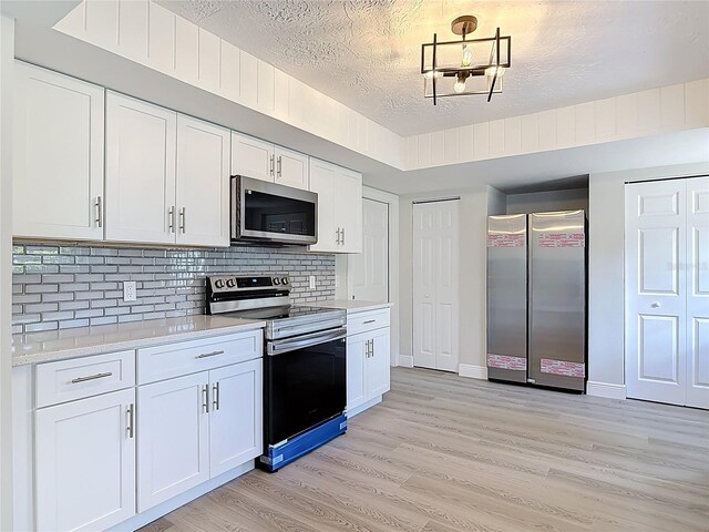1019 Chippewa Trl, Daytona Beach, FL 32117 - kitchen with appliances with stainless steel finishes, light wood-type flooring, light countertops, backsplash, and white cabinetry