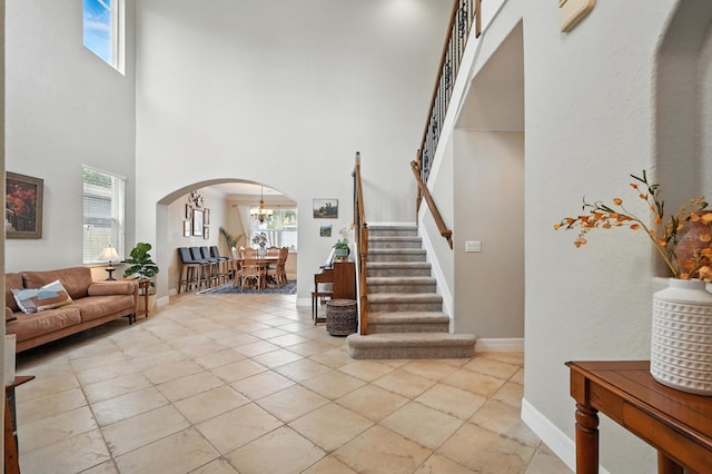 3842 Calliope Ave, Port Orange, FL 32129 - foyer entrance featuring arched walkways, a towering ceiling, stairway, light tile patterned flooring, and a chandelier