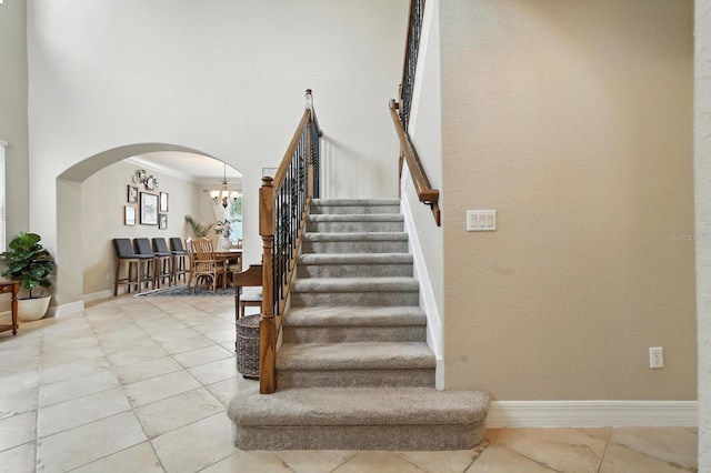 3842 Calliope Ave, Port Orange, FL 32129 - staircase with arched walkways, crown molding, a chandelier, and a towering ceiling