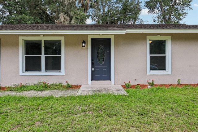 330 Ponce Deleon Blvd, De Leon Springs, FL 32130 - view of exterior entry with a yard, stucco siding, and roof with shingles
