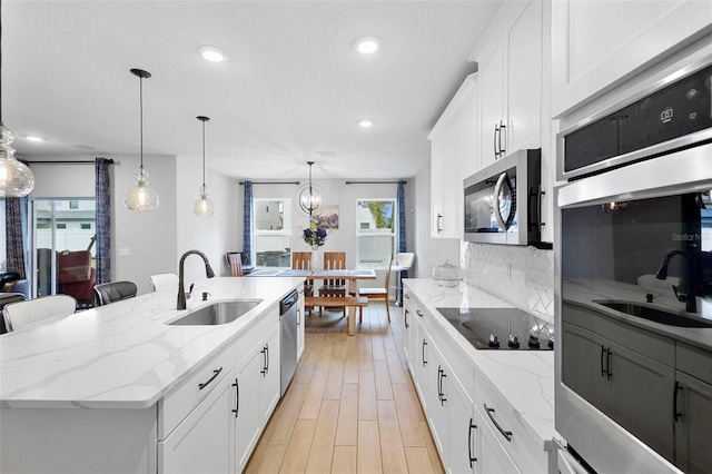 2807 Priego Blvd, Kissimmee, FL 34744 - kitchen with appliances with stainless steel finishes, a center island with sink, recessed lighting, light wood-style flooring, and decorative light fixtures