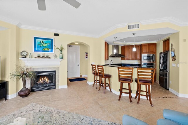 3343 S Atlantic Ave Unit 601, Daytona Beach Shores, FL 32118 - kitchen featuring wall chimney exhaust hood, stainless steel appliances, dark countertops, light tile patterned floors, and crown molding