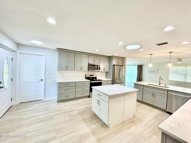 2017 Old Daytona Rd, Port Orange, FL 32128 - kitchen featuring stainless steel appliances, gray cabinetry, a kitchen island, light countertops, and light wood-style flooring