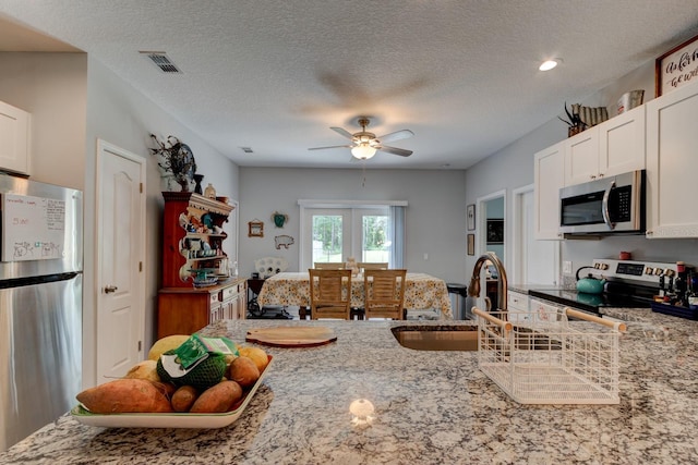 5005 Joseph St, Hastings, FL 32145 - kitchen with stainless steel appliances, light stone countertops, a ceiling fan, white cabinetry, and a textured ceiling