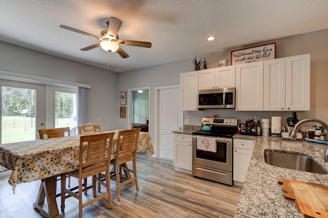 5005 Joseph St, Hastings, FL 32145 - kitchen featuring appliances with stainless steel finishes, light wood-style floors, white cabinets, light stone counters, and ceiling fan
